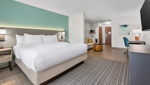 Una habitación de hotel con cama, mesita de noche, lámpara, escritorio, silla y televisor.