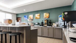 Una cocina moderna con una isla central, taburetes de bar y varios electrodomésticos.