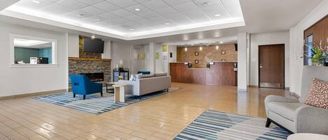 A spacious lobby with a reception desk, seating area, and a kitchen in the background.