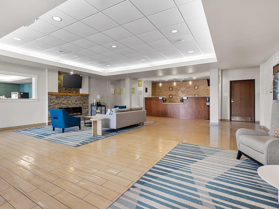 A spacious lobby with a reception desk, seating area, and a kitchen in the background.