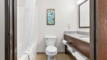 A bathroom with a toilet, shower curtain, towel rack, and a framed abstract painting.