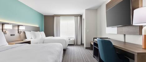 A hotel room with two beds, a desk, a chair, a TV, and a window with curtains.