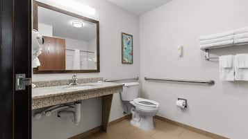 A modern bathroom with a granite countertop sink, a toilet, a hand dryer, a towel rack, and a hand sanitizer dispenser.