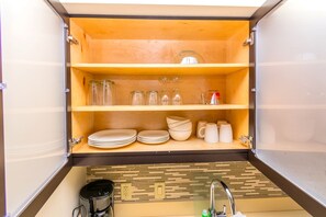 A compact kitchen with wooden shelves, a coffee maker, and a sink.