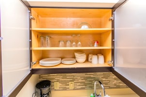 A compact kitchen with wooden shelves, a coffee maker, and a sink.