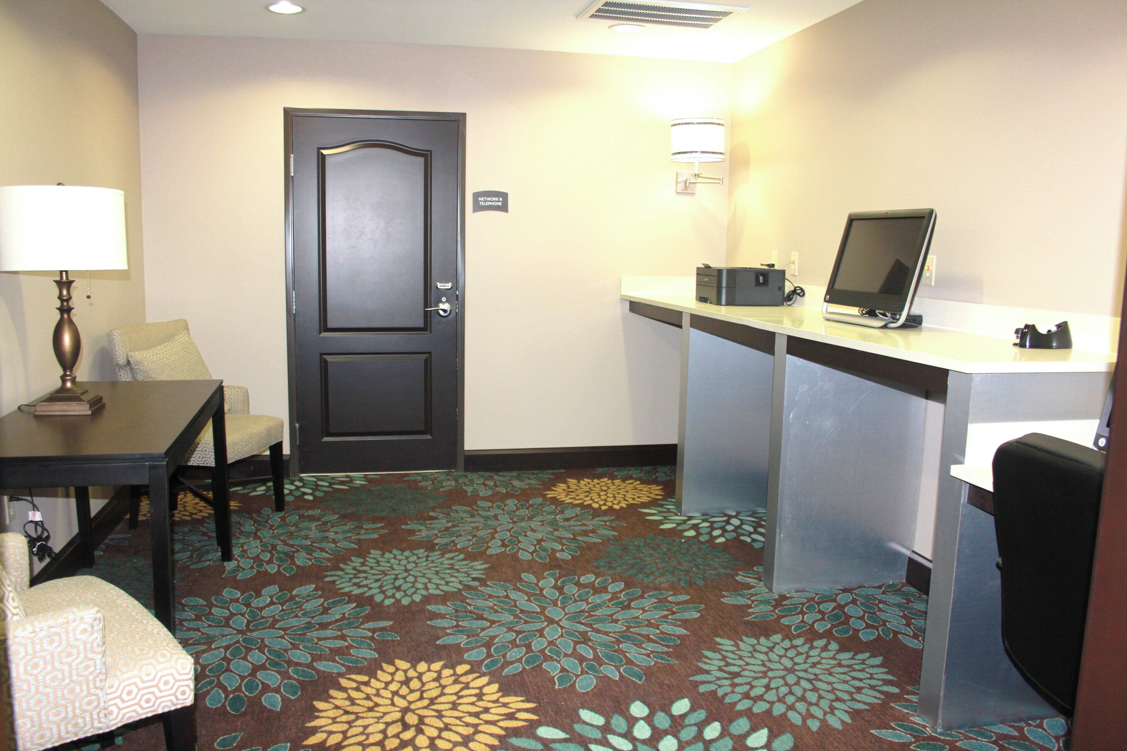 Une chambre d’hôtel équipée d’un bureau, d’une chaise, d’une lampe et d’une porte avec une pancarte.