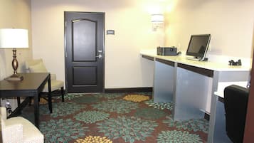 Une chambre d’hôtel équipée d’un bureau, d’une chaise, d’une lampe et d’une porte avec une pancarte.