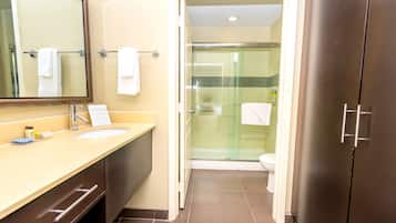 Un baño moderno con lavamanos, espejo y ducha con mampara de vidrio.