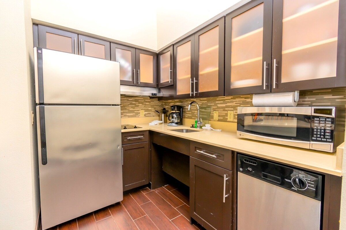 A compact kitchen with a refrigerator, microwave, coffee maker, and dishwasher.