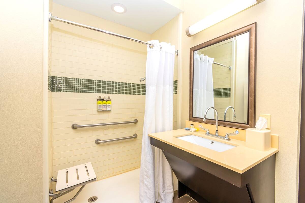 A bathroom with a bathtub, a sink with a mirror, and a shower with a curtain.