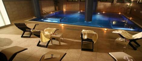 A spa area with a hot tub, lounge chairs, and small tables.