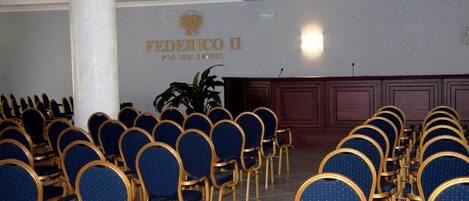 A conference room with rows of blue chairs and a podium at the front.