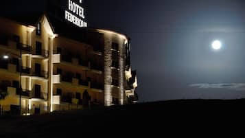 Un hotel con un cartel llamativo, varios balcones y una luna en el cielo.