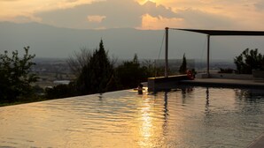 A swimming pool with a view of mountains and a sunset.