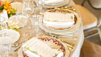 A table set for a formal event with white tablecloths, gold-rimmed plates, and clear glassware.