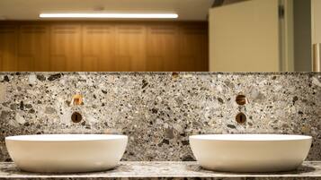 A bathroom with two white sinks, a speckled granite countertop, and wooden cabinets in the background.