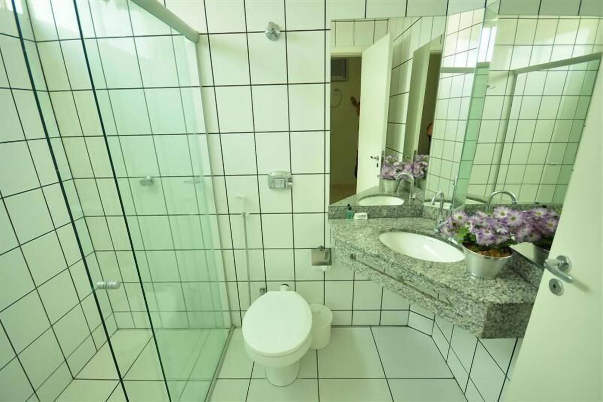 A bathroom with a white toilet, a sink with a granite countertop, and a mirror above the sink.
