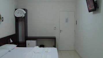 Una habitación de hotel con cama, escritorio, silla, televisor y puerta.
