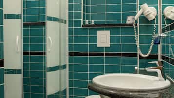 Een badkamer met een douchecabine van glas, een wit toilet en een wastafel met een granieten aanrecht.