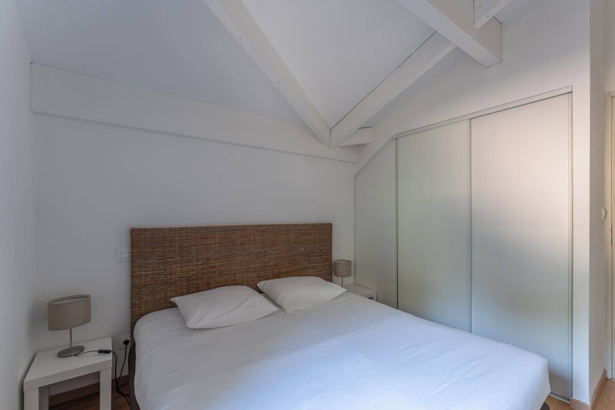 Un dormitorio con cama, mesita de noche, lámpara y armario.
