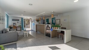 A modern reception area with a counter, seating, and a view to the outside. - Residence Les Rives du Lac - Vacancéole (Lacanau)