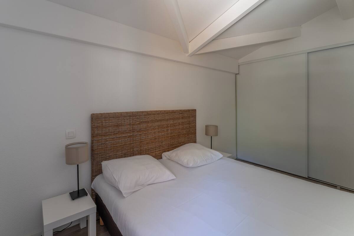 Un dormitorio con cama, mesitas de noche, una lámpara y un armario.