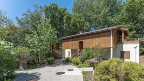 A modern building with a wooden exterior, a concrete pathway, and surrounding greenery. - Residence Les Rives du Lac - Vacancéole (Lacanau)