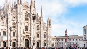 A historic cathedral with intricate Gothic architecture, large arched windows, and a prominent clock tower in the background. - Hotel Nuovo (Milan)
