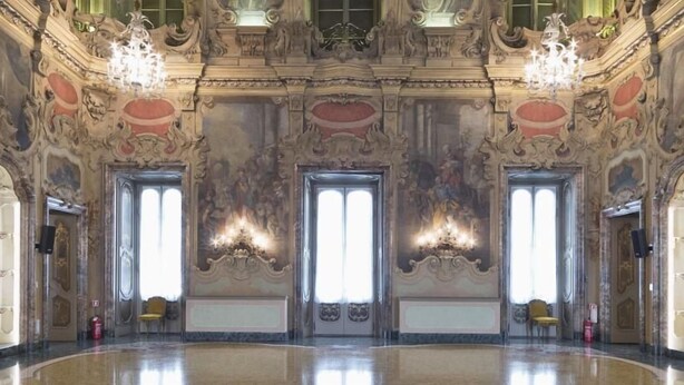 An ornate hall with three large doors, each with a chandelier. The walls are decorated with intricate designs and there are two chairs visible. - Hotel Nuovo (Milan)