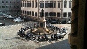 A plaza with a central monument surrounded by parked motorcycles. - Hotel Nuovo (Milan)