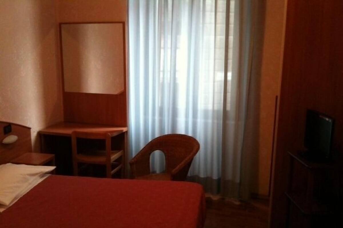 Une chambre d’hôtel avec un lit, un bureau, une chaise et un téléviseur.