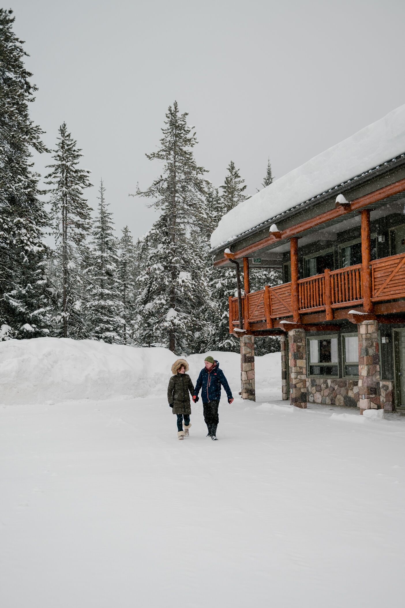 A lodge with a stone and wood exterior, surrounded by snow-covered trees.