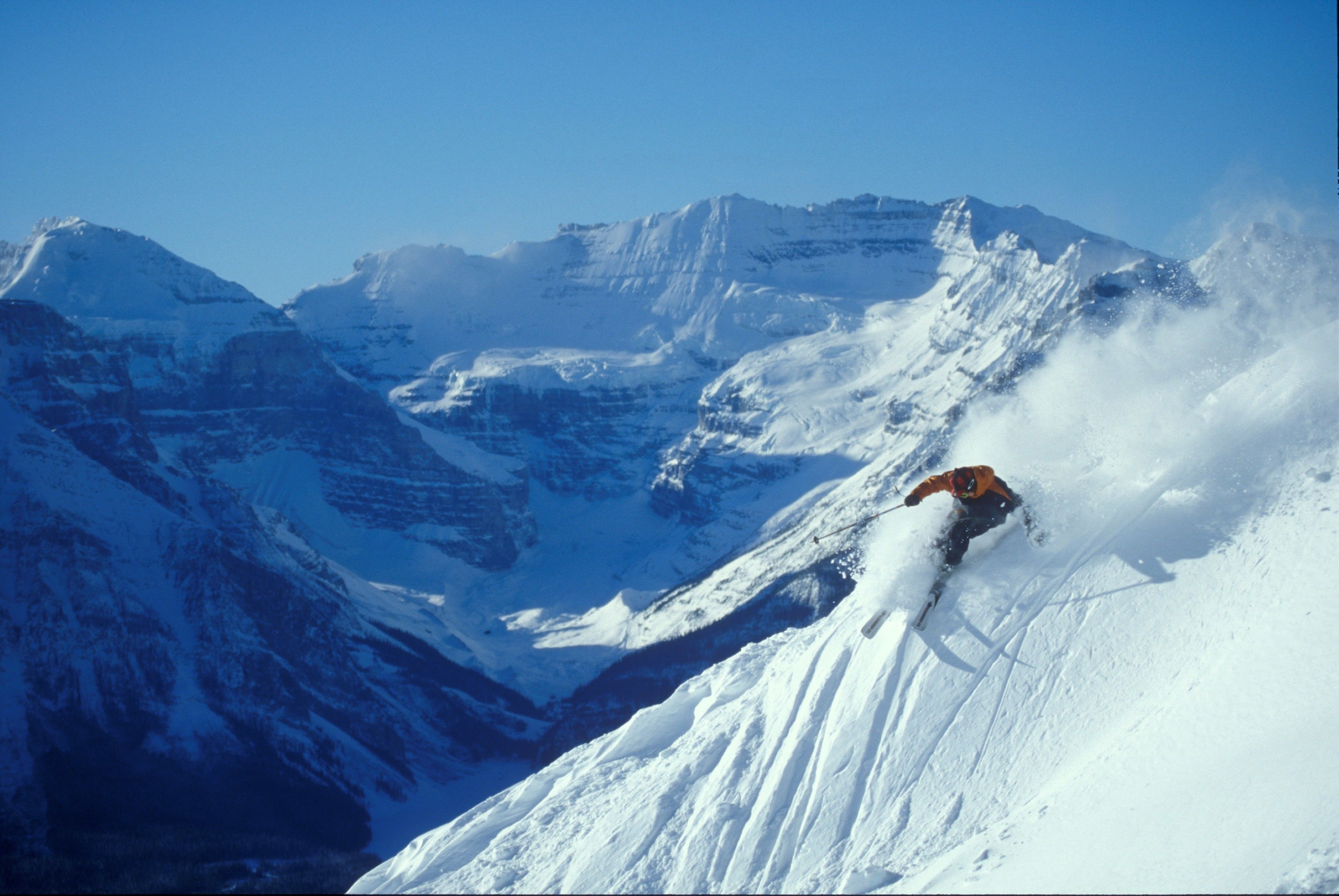 Un paysage de montagne enneigé avec un skieur en mouvement.