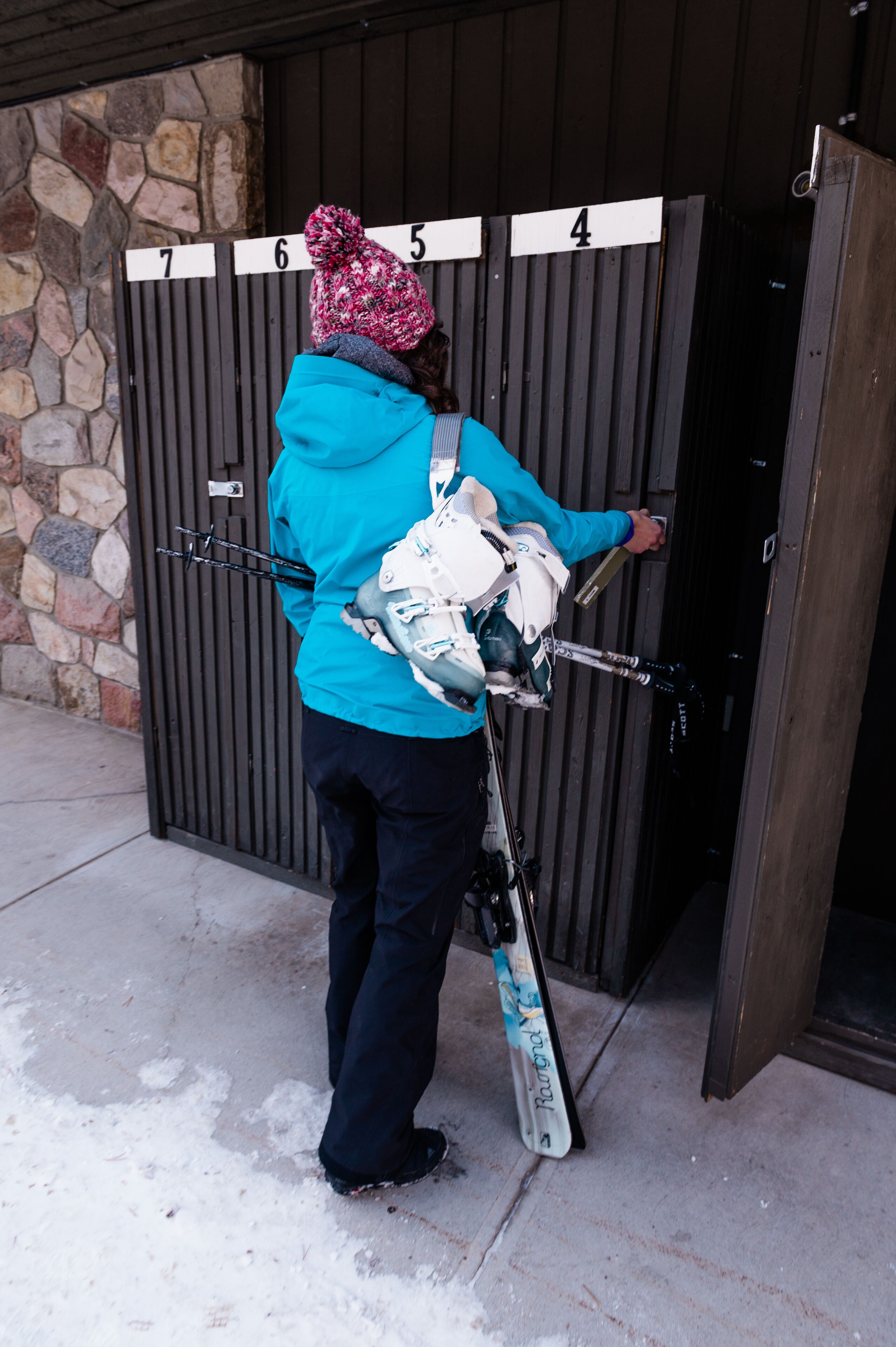 Une personne équipée de skis, debout devant une porte numérotée, tenant un bâton de ski.