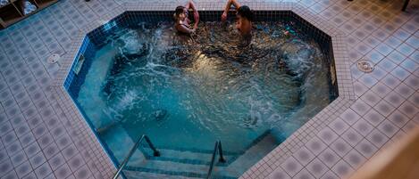 Een jacuzzi met twee personen, omgeven door een betegelde vloer.