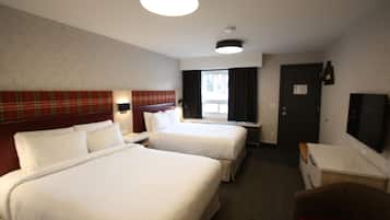 Habitación de hotel con dos camas, un escritorio, una silla, un televisor y una ventana con cortinas.