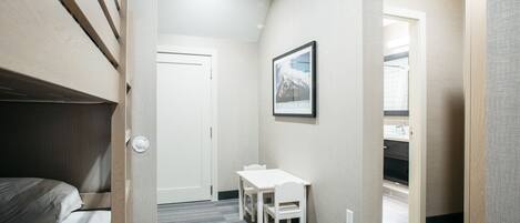 A hotel room with a bed, a small table with chairs, a framed picture on the wall, and a door leading to a bathroom.