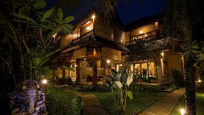 A two-story wooden house with a balcony, surrounded by lush tropical vegetation. - Bliss Bungalow (Ubud)