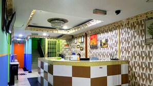 Uma área de recepção com balcão quadriculado, um candelabro e paredes estampadas.