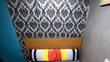 Una cama con colcha a rayas, almohadas y dos toallas dobladas sobre un corredor de cama marrón.
