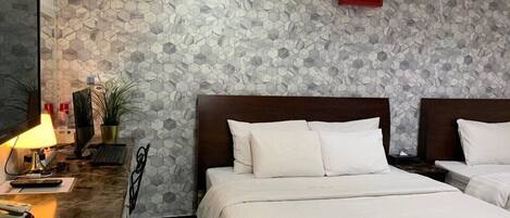 A hotel room with a marble desk, a bed with white linens, a headboard, and a wall with a hexagonal pattern.