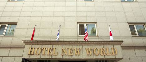 Un edificio con el letrero "HOTEL NEW WORLD" y varias banderas en la fachada.