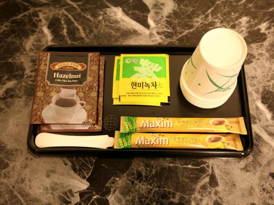 Una bandeja con un filtro para café, una taza de café y dos sobres de café instantáneo Maxim.