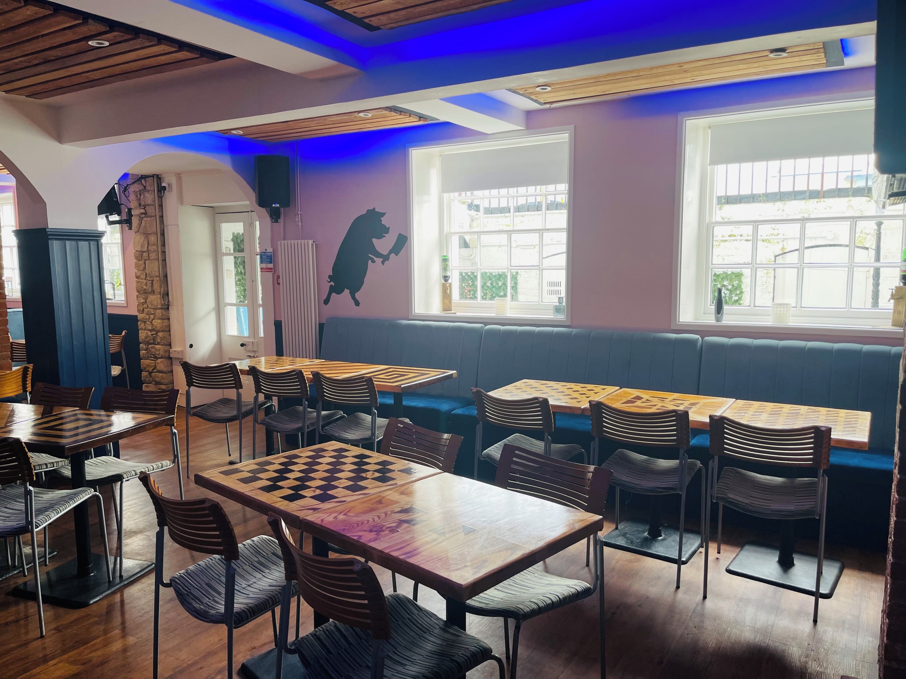 A cozy cafe with wooden tables, cushioned seating, and a large window with a view.