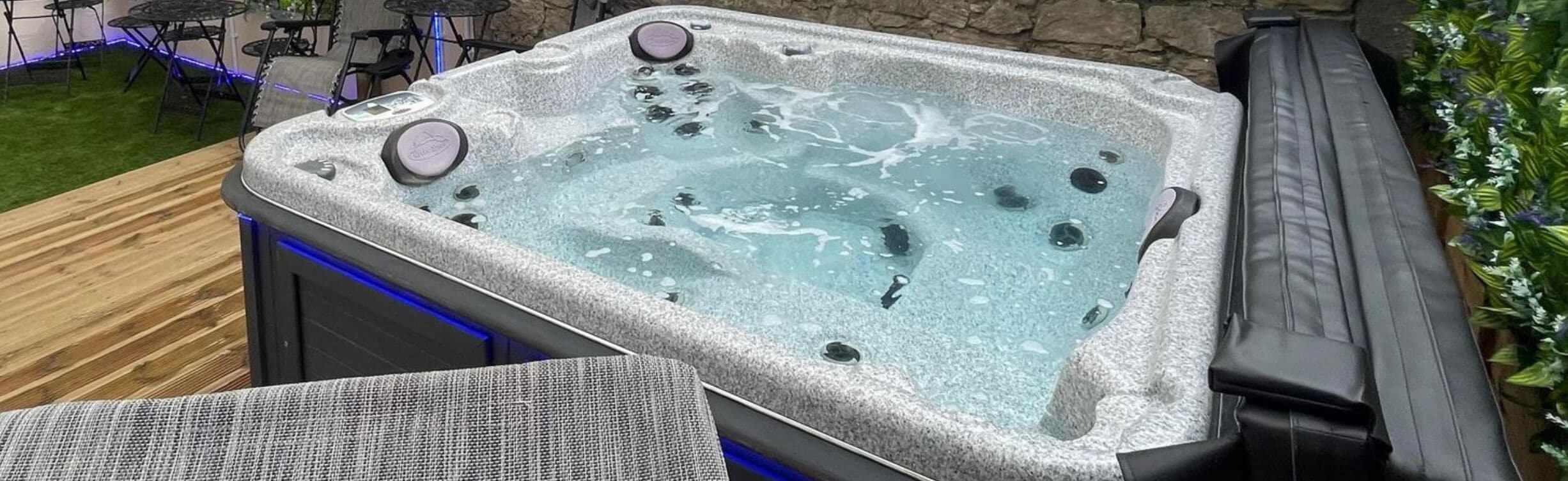 A hot tub with a stone exterior, surrounded by a wooden deck and outdoor furniture.