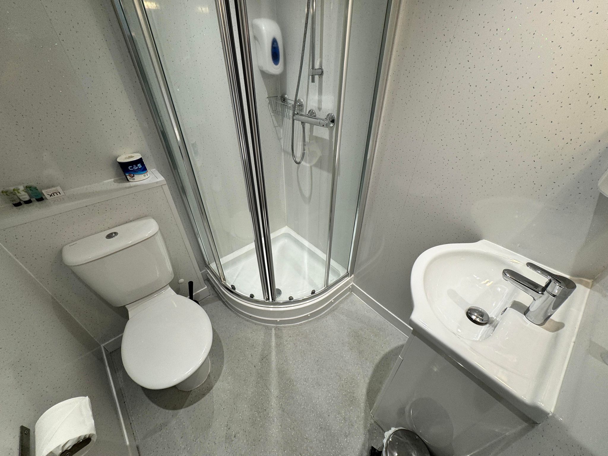 A modern bathroom with a glass-enclosed shower, a toilet, and a sink.