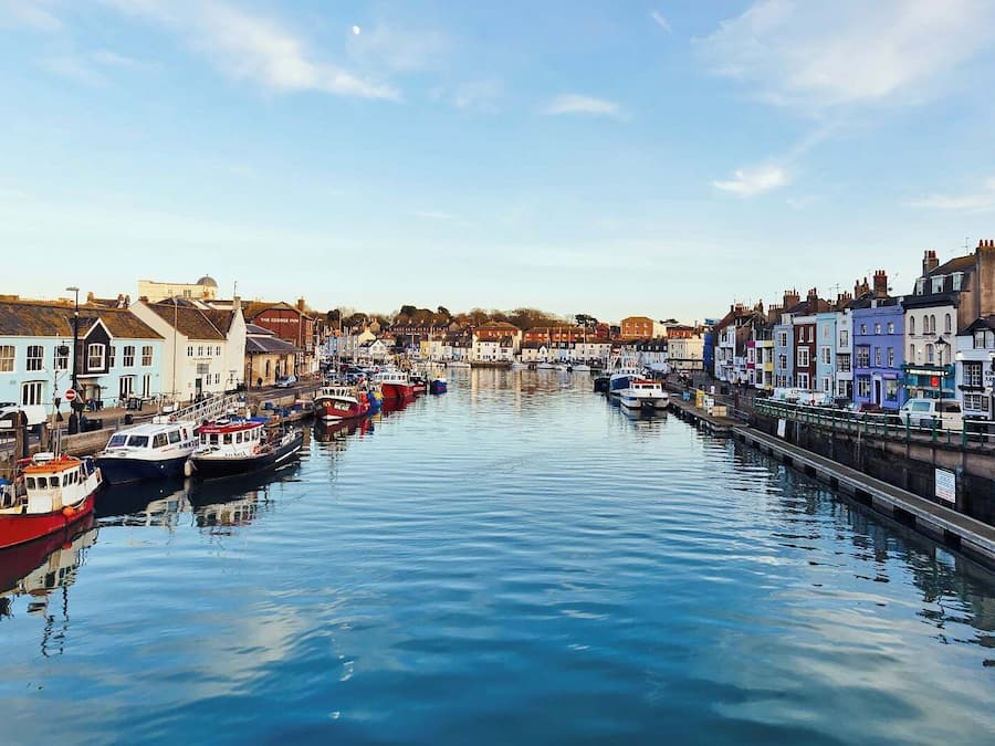 A canal lined with buildings, boats docked along the water, and a clear sky.