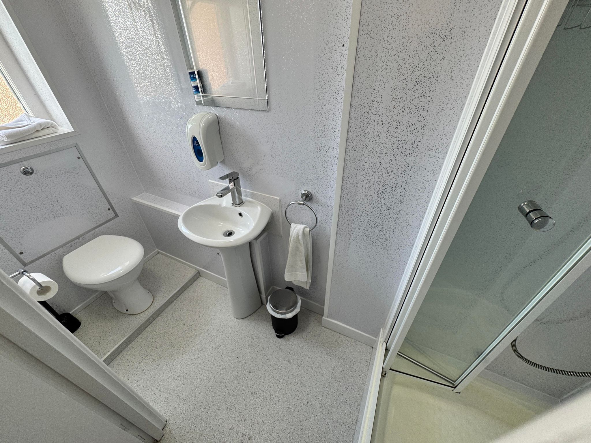 Un baño con lavamanos, inodoro y ducha blancos.