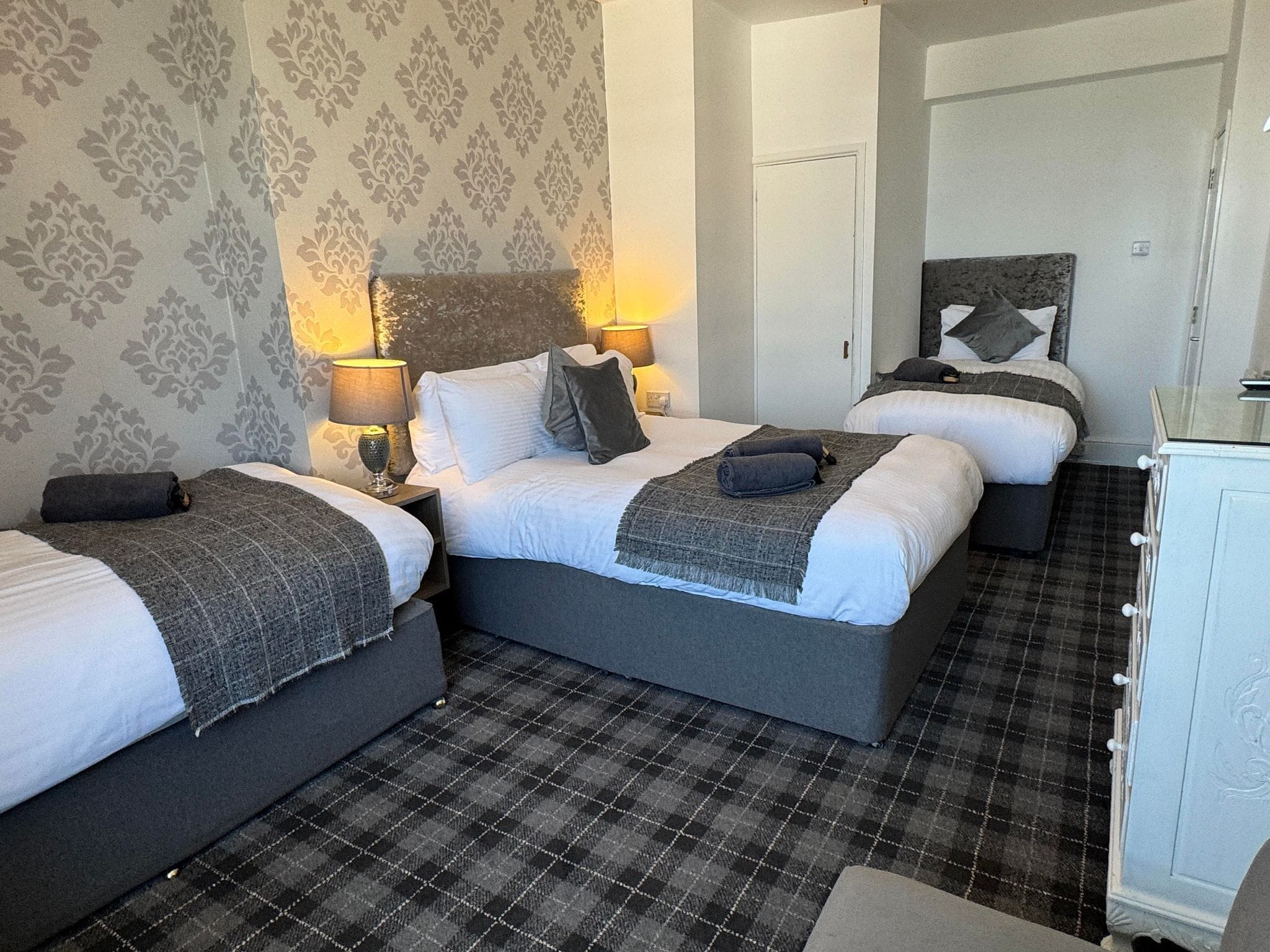 A hotel room with two beds, a wardrobe, and a patterned carpet.