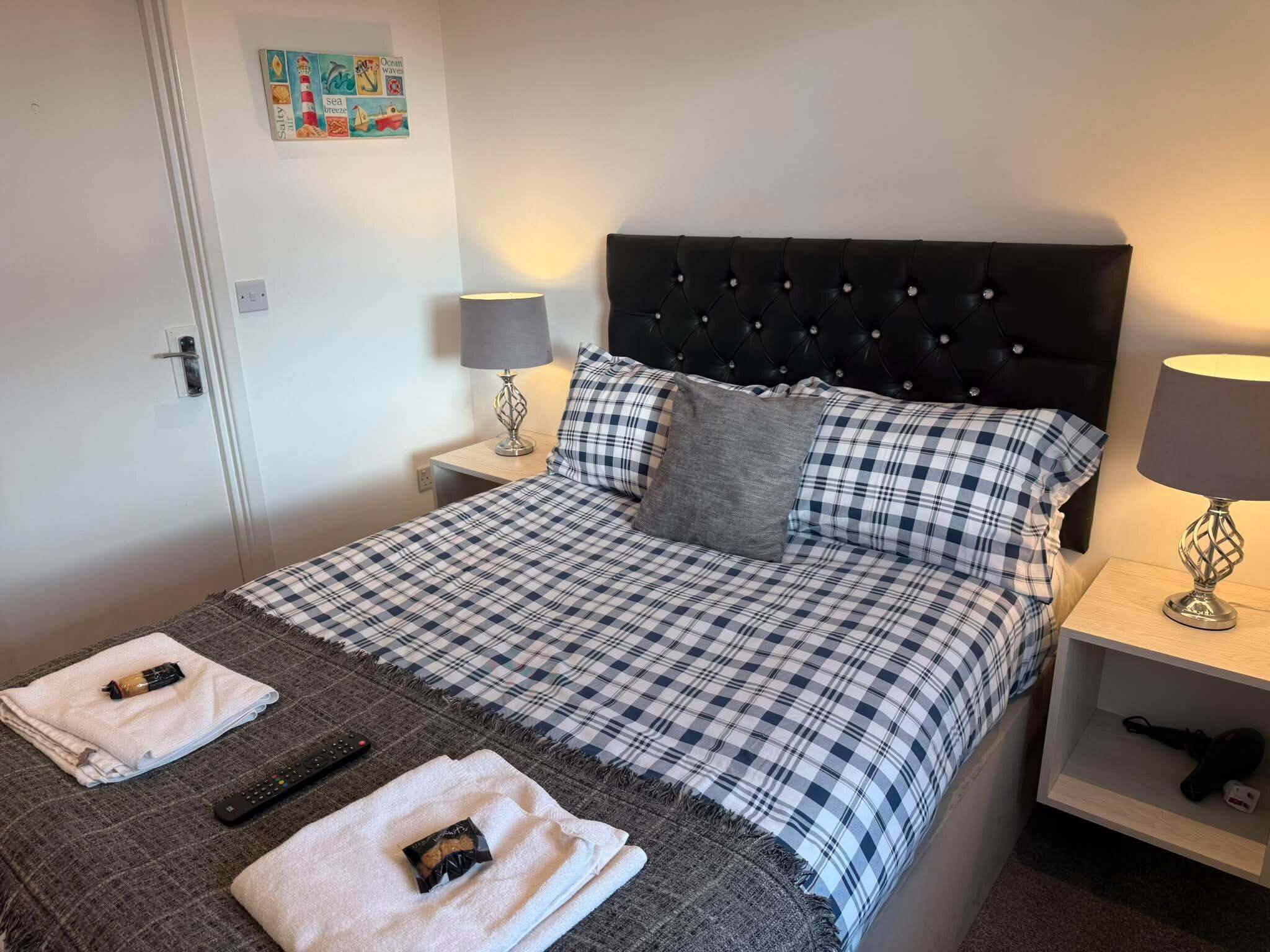 Une chambre d’hôtel comprenant un lit, deux tables de chevet, une lampe et un élément de décoration murale.